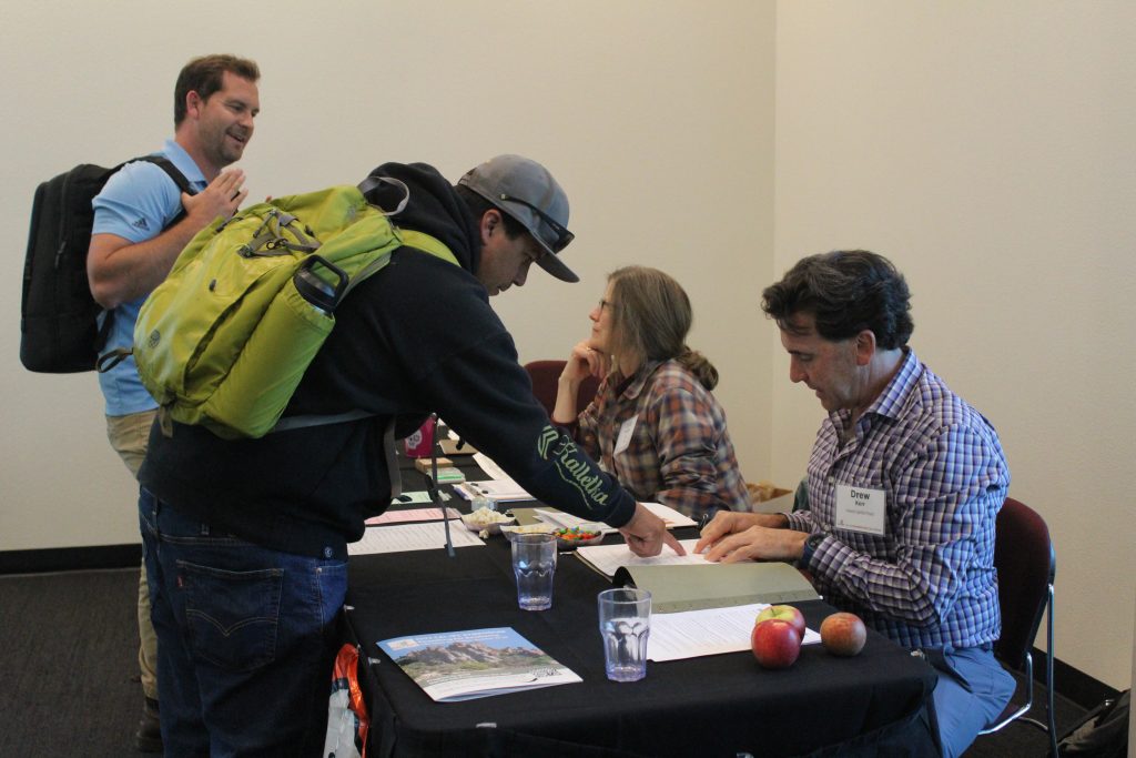 People in an event lobby at a tablecloth covered desk help visitors